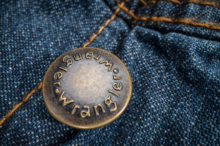 Fort Collins, CO, USA - November 14, 2022: Closep of Wrangler metal button on a trucker denim jacket. Wrangler is American manufacturer of jeans and other clothing.のeditorial素材