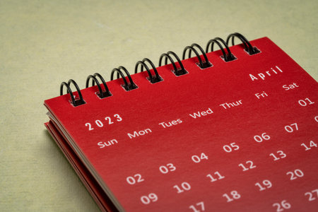 April 2023 - small spiral desktop calendar against textured paper, time and business conceptの写真素材