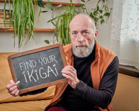 find your ikigai inspirational reminder note, chalk writing on a blackboard held by an old, wise man - Japanese concept of a reason for being and life purposeの写真素材