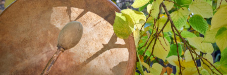 handmade, native American style, shaman frame drum with a beater against fall foliageの写真素材
