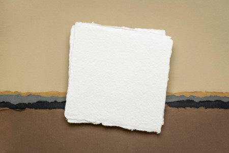 small square sheet of blank white paper against abstract landscape in earth tonesの写真素材