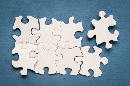 top view of white blank unfinished jigsaw puzzle on blue background, completing a task or solving a problem conceptの写真素材