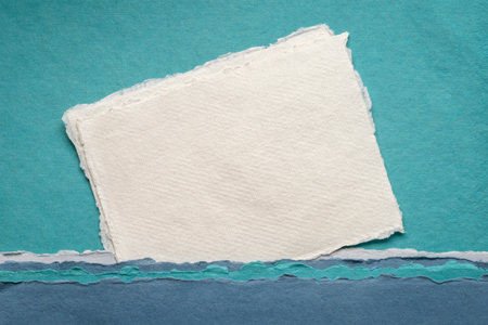 small sheet of blank white Khadi rag paper from India against abstract landscape in blue tonesの写真素材
