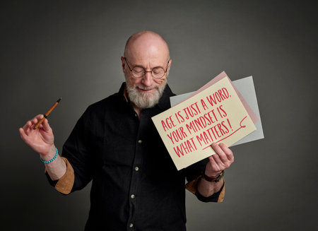 Age is just a word. Your mindset is what matters! Inspirational note held by a happy, positive senior man.の写真素材