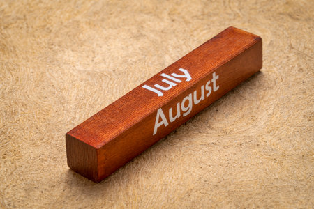 July and August text on wooden block against handmade bark paper in earth tones, calendar conceptの写真素材