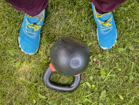 heavy iron kettlebell and male feet on a grass, backyard fitness conceptの写真素材