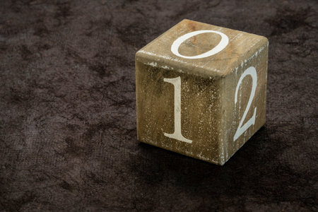numbers 0, 1, and 2 on a wooden, grunge cube against black art paperの写真素材