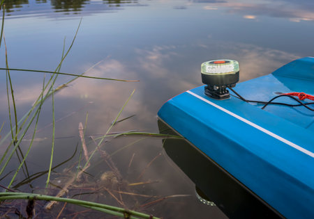 white navigational light on a tail of touring stand up paddleboard - summer dusk over lake in...
