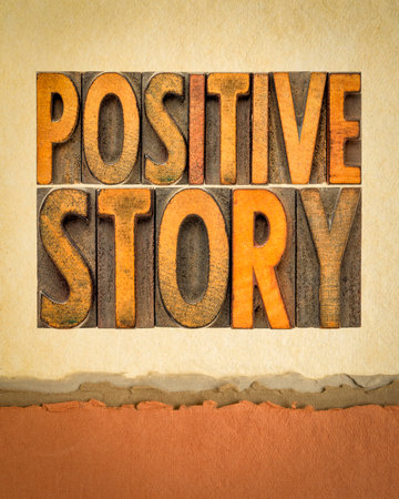 positive story word abstract in vintage wood type on art paper, good news or success conceptの写真素材