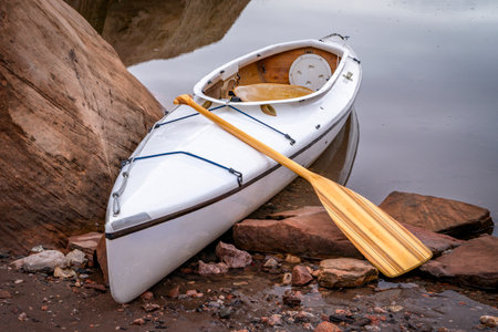 decked expedition canoe with a wooden paddle on a rocky shore of Horsetooth Reservoir near Fort Collins, Colorado, low water level fall or winter sceneryの写真素材