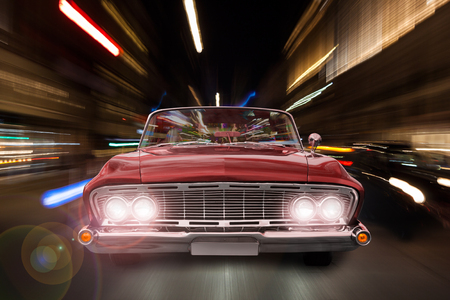 Sports car drives at night through the lights of the cityの写真素材
