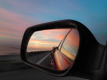 The side mirror of a car reflects the evening skyの写真素材