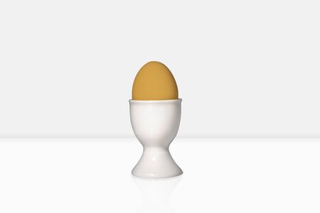 A brown egg in an eggcup stands in a white environmentの写真素材