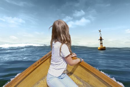 A girl in a wooden boat swims towards a buoyの写真素材