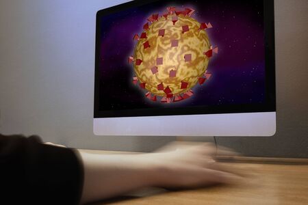 A hand moves the computer mouse and a virus is visible on the monitorの写真素材