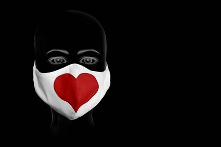 The silhouette of a head is wearing a face mask with a red heartの写真素材