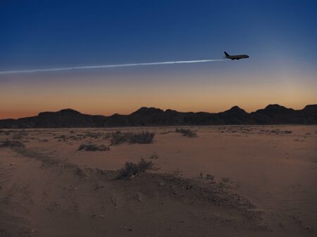 The silhouette of an airplane at dusk over the desertの写真素材