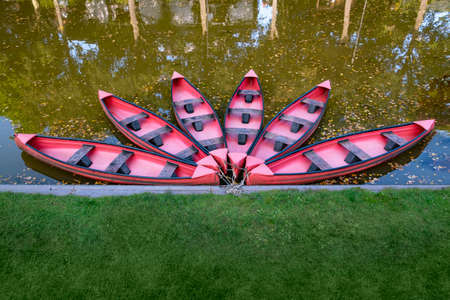 Six red canoes in a pond