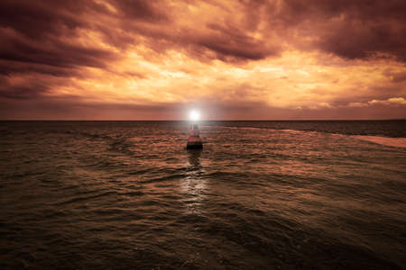 A yellow buoy drifts in the sea at dusk