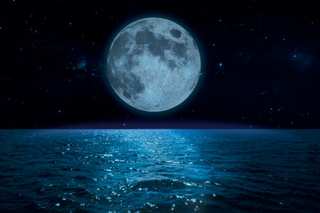 The full moon is reflected in the ocean waves on the starry nightの写真素材