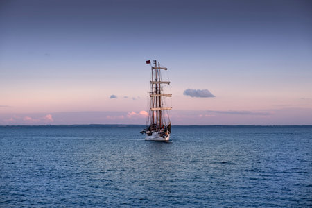 A three-master sails across the sea as dusk fallsの写真素材