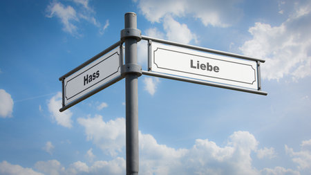 An image with a signpost pointing in two different directions in German. One direction points to love, the other points to hate.の写真素材