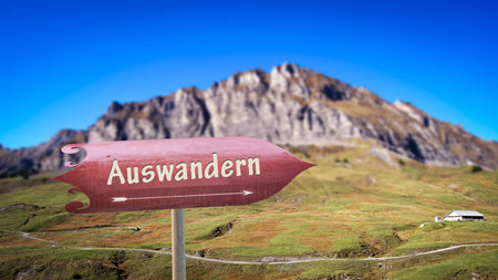 Image shows a signpost and a sign in the direction of emigration and wanderlust in German.の写真素材