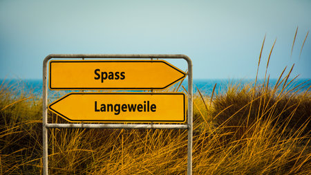 An image with a signpost pointing in two different directions in German. One direction points to fun, the other points to boredom.の写真素材