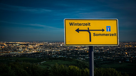An image with a signpost in German pointing towards winter time.の写真素材