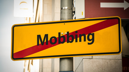 An image with a signpost pointing in two different directions in German. One direction points to motivation, the other points to bullying.の写真素材