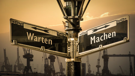 An image with a signpost pointing in two different directions in German. One direction is to do, the other is to wait.の写真素材