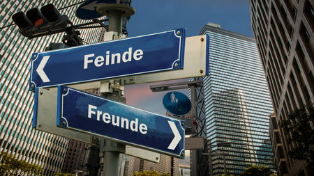 An image with a signpost pointing in two different directions in German. One direction points to friends, the other points to enemies.の写真素材