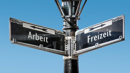 An image with a signpost pointing in two different directions in German. One direction points to free time, the other points to work.の写真素材
