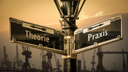 An image with a signpost pointing in two different directions in German. One direction points to practice, the other points to theory.の写真素材