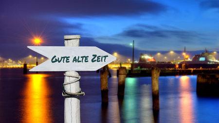 the picture shows a signpost and a sign that points in the direction of good old times in german.の写真素材