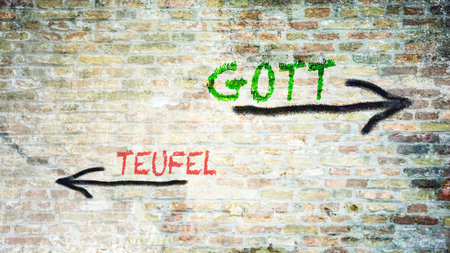 An image with a signpost pointing in two different directions in German. One direction points to God, the other points to the devil.の写真素材
