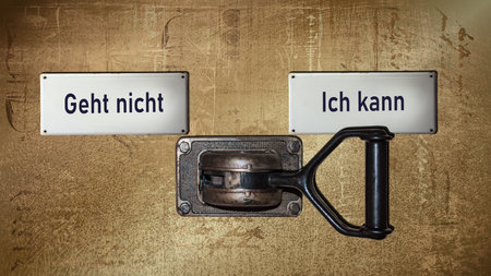 An image with a signpost pointing in two different directions in German. One direction points to I can, the other points to resignation.の写真素材
