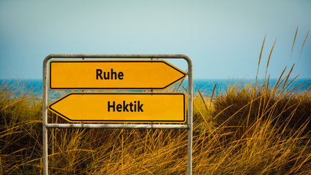An image with a signpost pointing in two different directions in German. One direction points to rest, the other to hectic.の写真素材