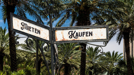 An image with a signpost pointing in two different directions in German. One direction points to buy, the other points to rent.の写真素材