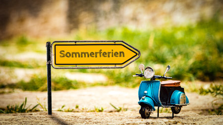An image with a signpost in German pointing in the direction of summer vacation.の写真素材