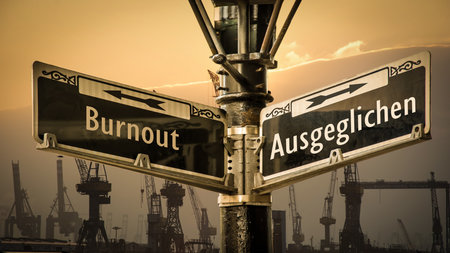 An image with a signpost pointing in two different directions in German. One direction points to Balanced, the other points to Burnoutの写真素材