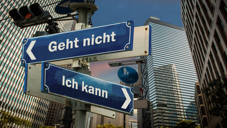 An image with a signpost pointing in two different directions in German. One direction points to I can, the other points to resignation.の写真素材