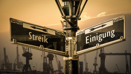 An image with a signpost pointing in two different directions in German. One direction points to agreement, the other points to strike.の写真素材