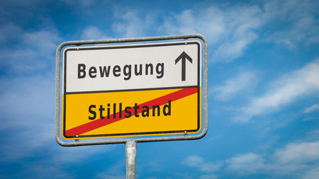 An image with a signpost pointing in two different directions in German. One direction points to move, the other points to standstill.の写真素材