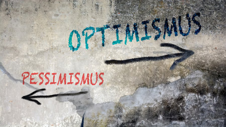 An image with a signpost pointing in two different directions in German. One direction points to optimism, the other points to pessimism.の写真素材