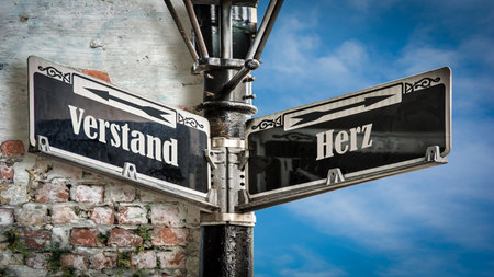 An image with a signpost pointing in two different directions in German. One direction points to the word 'Verstand' (mind), the other points to the word 'Herz' (heart).の写真素材