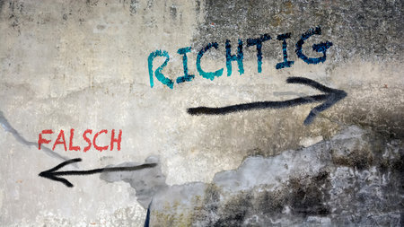 An image with a signpost pointing in two different directions in German. One direction points right, the other points wrong.の写真素材