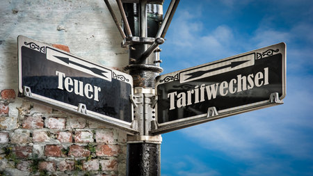 An image with a signpost pointing in two different directions in German. One direction points to Tariff Change, the other points to Expensive.の写真素材