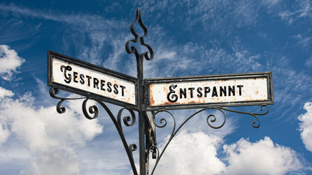 An image with a signpost pointing in two different directions in German. One direction points to Relaxed, the other points to Stressed.の写真素材