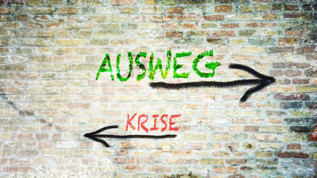 An image with a signpost pointing in two different directions in German. One direction points to a way out, the other points to a crisis.の写真素材